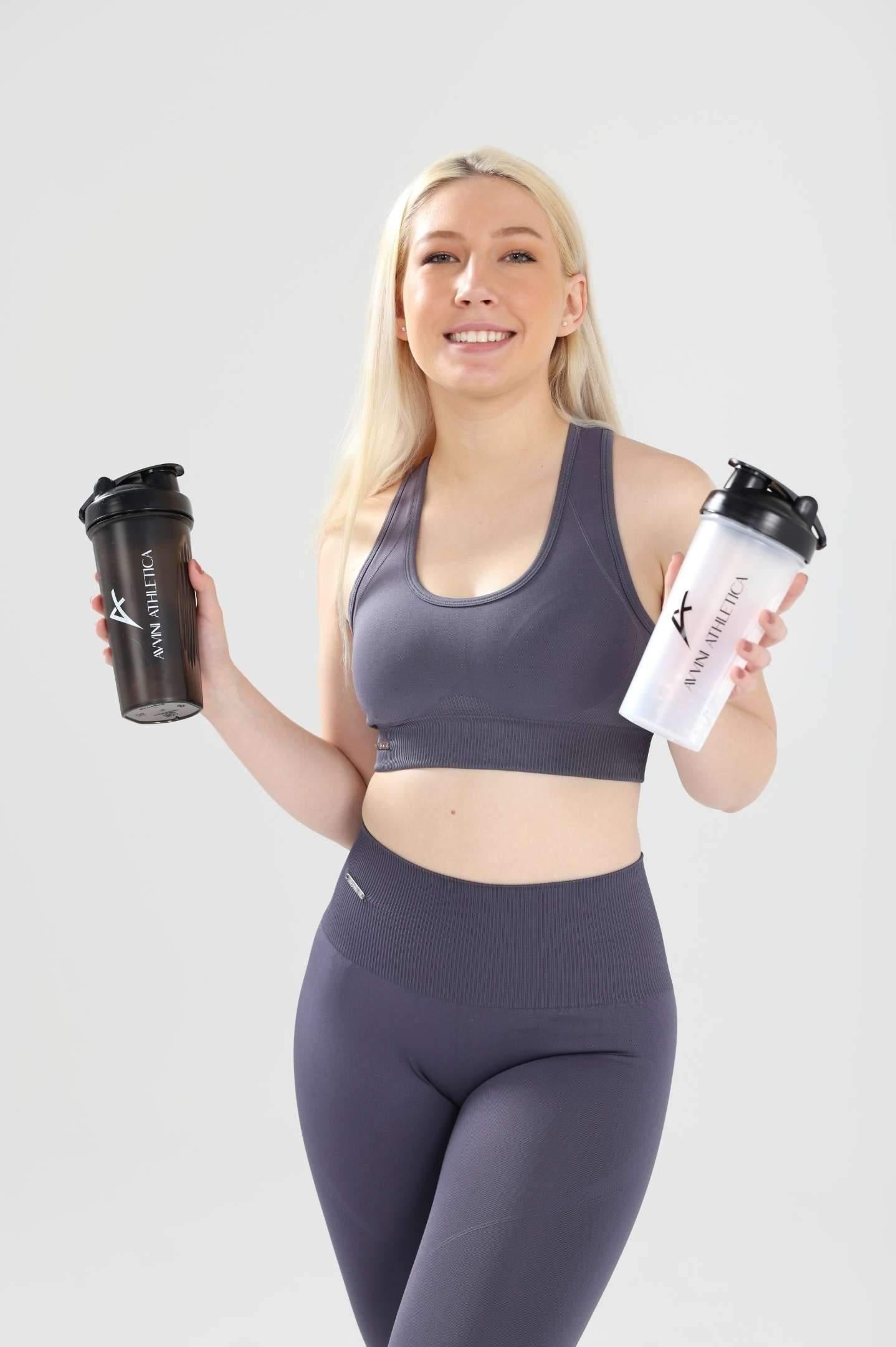 Girl smiling wearing Invictus set in charcoal holding one white and one black shaker bottle in each hand 