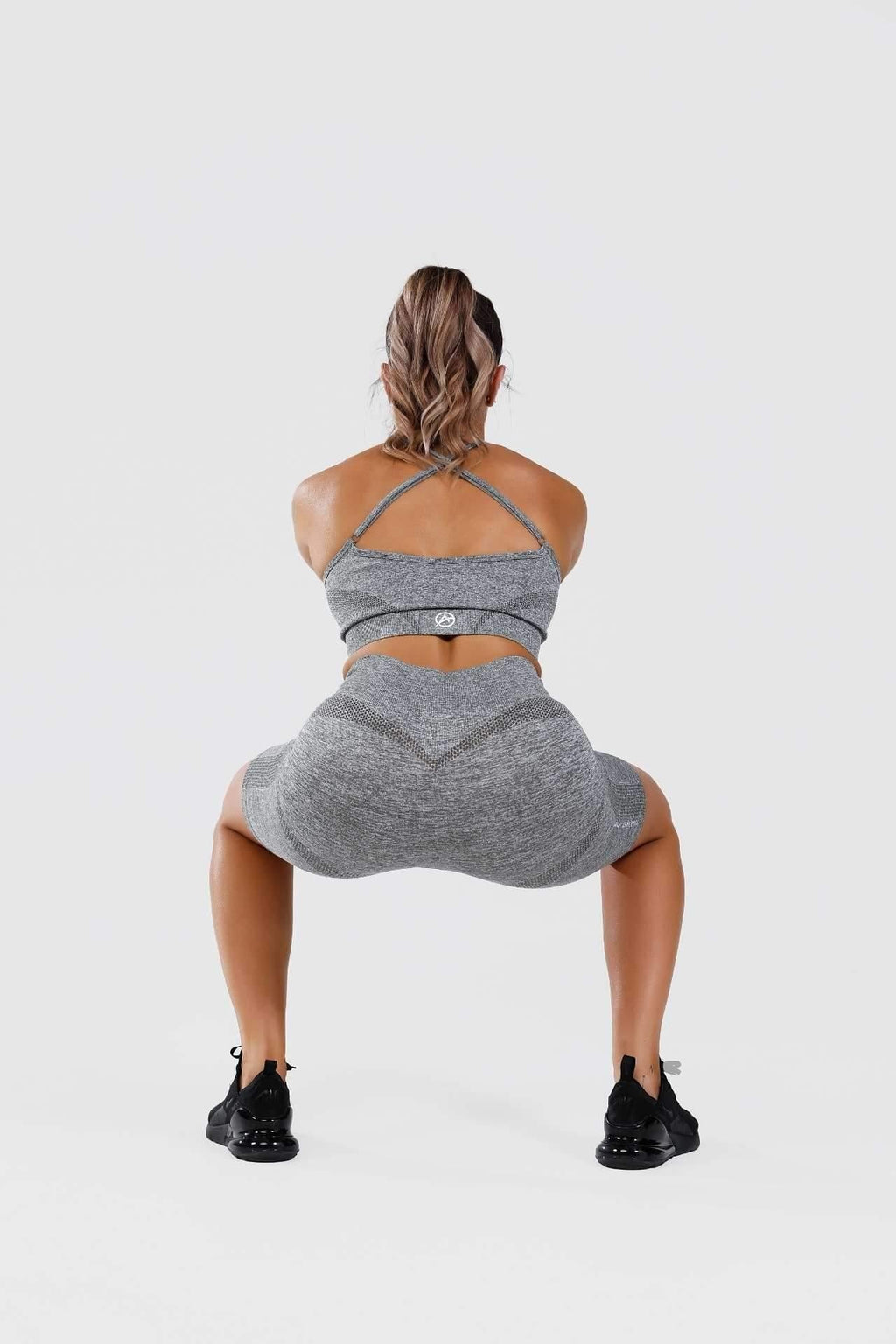 Girl holding squat in grey calypso seamless set, back shot