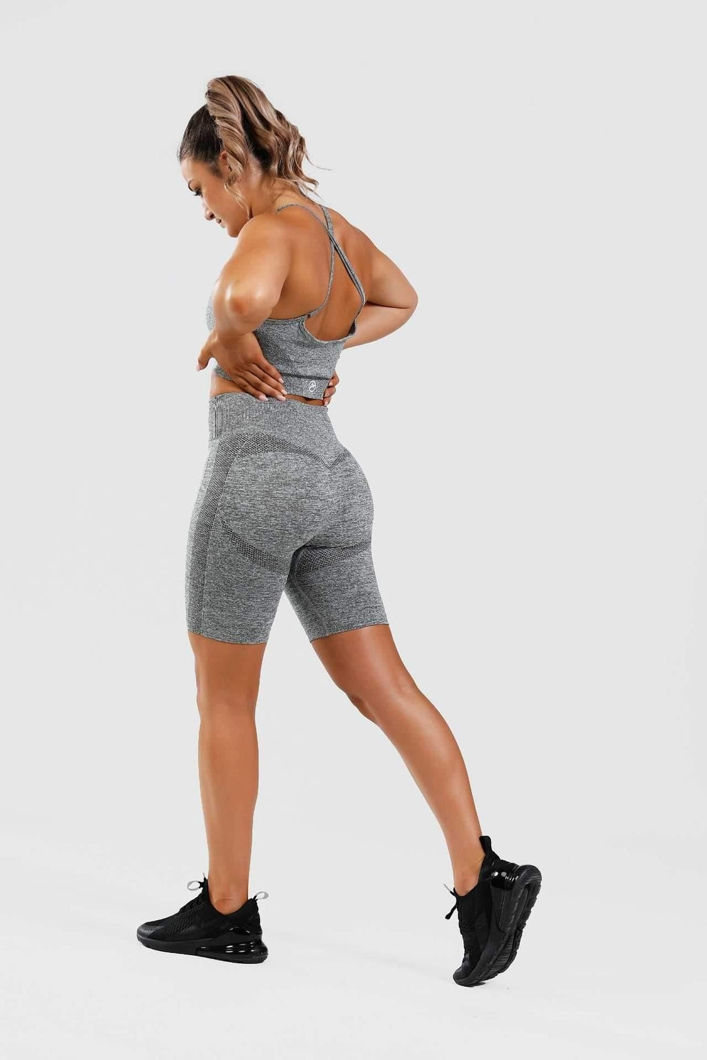 Girl posing hands on hips wearing grey calypso seamless set from behind