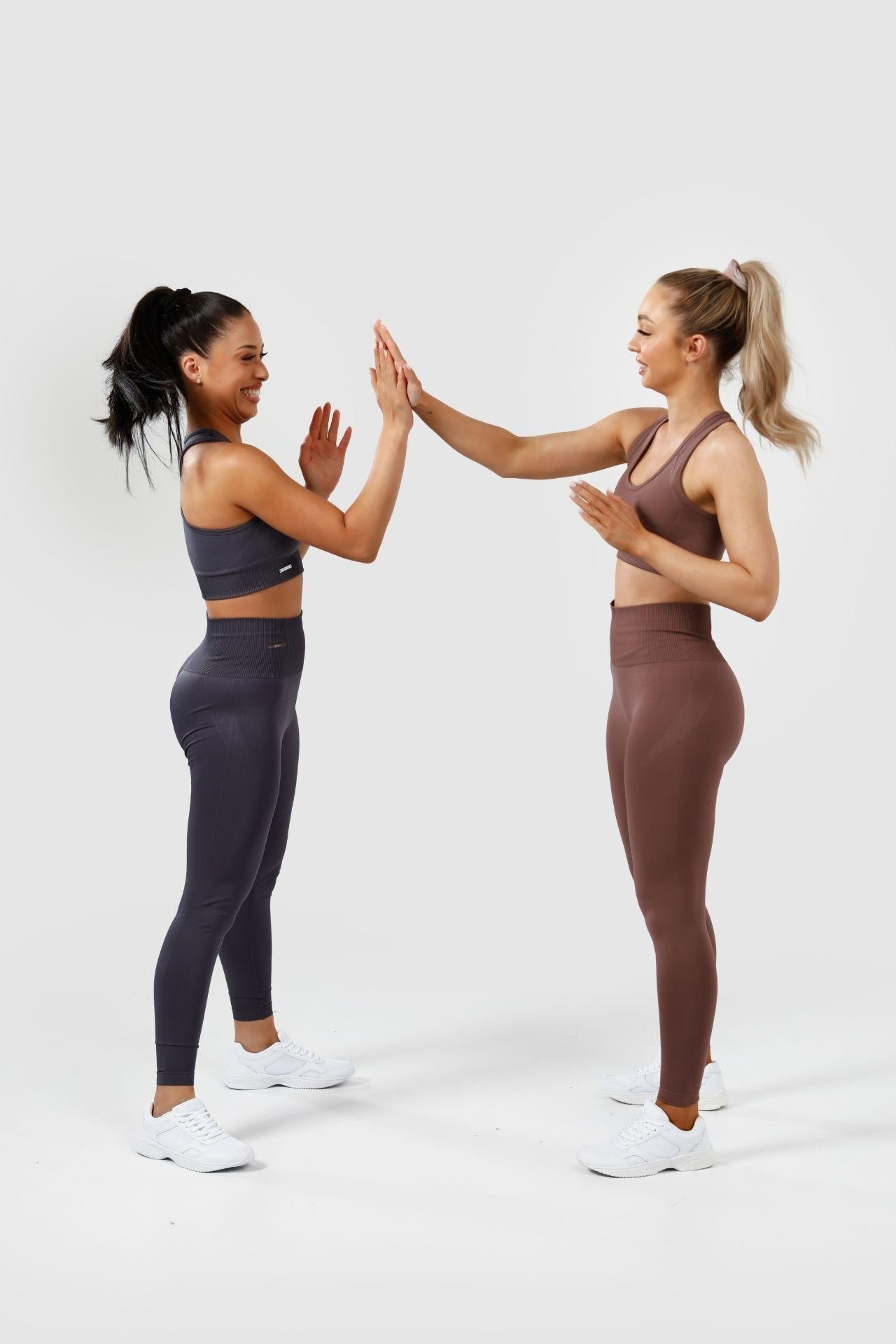 Girls wearing charcoal and mauve purple invictus seamless sets clapping hands