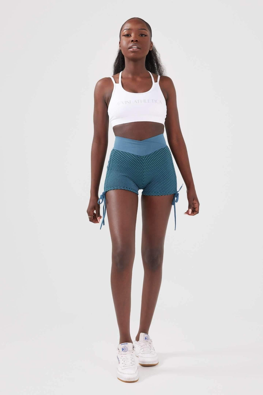 Full length shot girl wearing blue scrunch bum shorts with white crop top